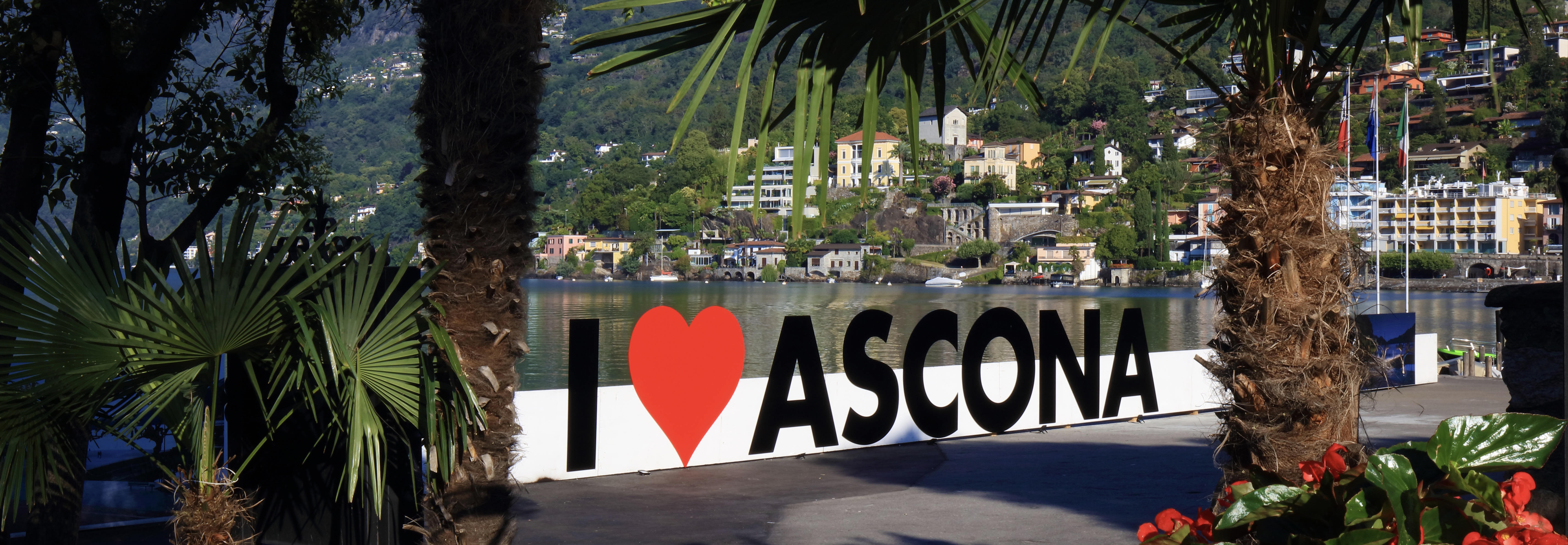 Palm-framed I heart Ascona sign along the lakeside promenade