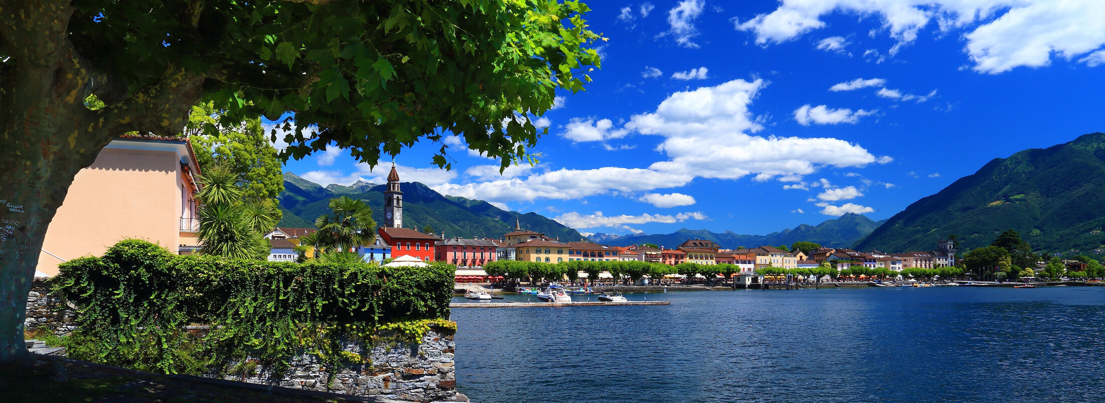 Sunny view across the Ascona waterfront and Lago Maggiore with mountains beyond